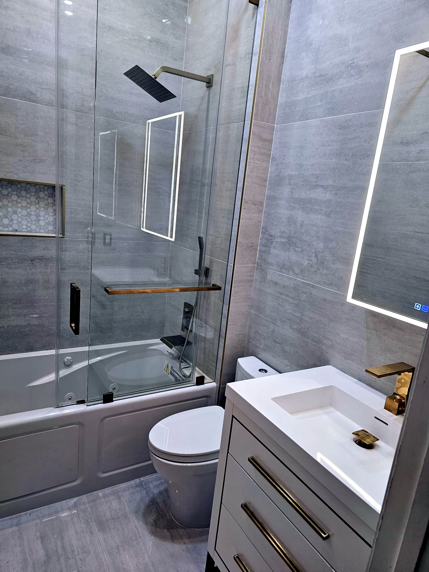 Guest bathroom with porcelain tile, gold fixtures and LED mirror