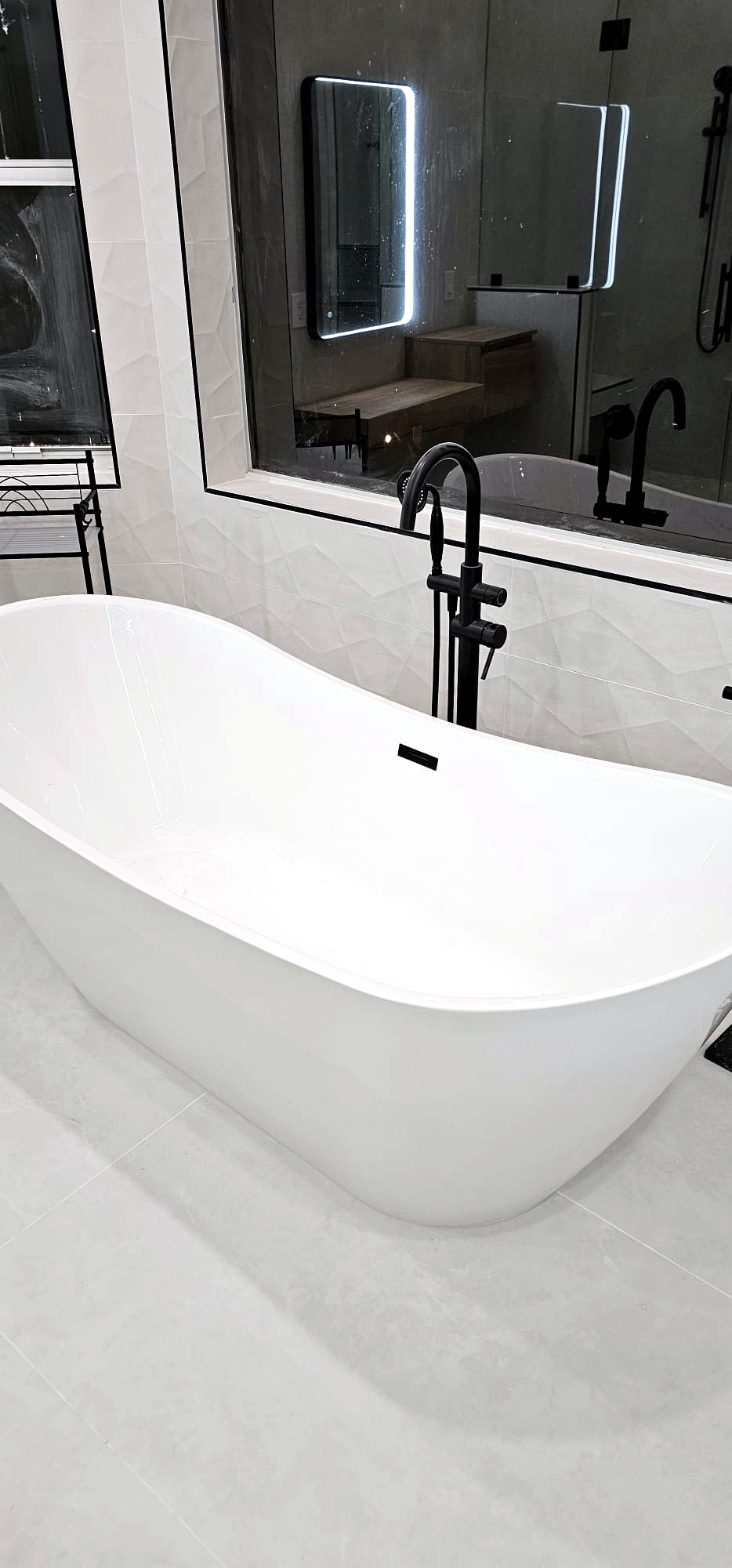 Freestanding soaking tub with matte black floor-mount faucet