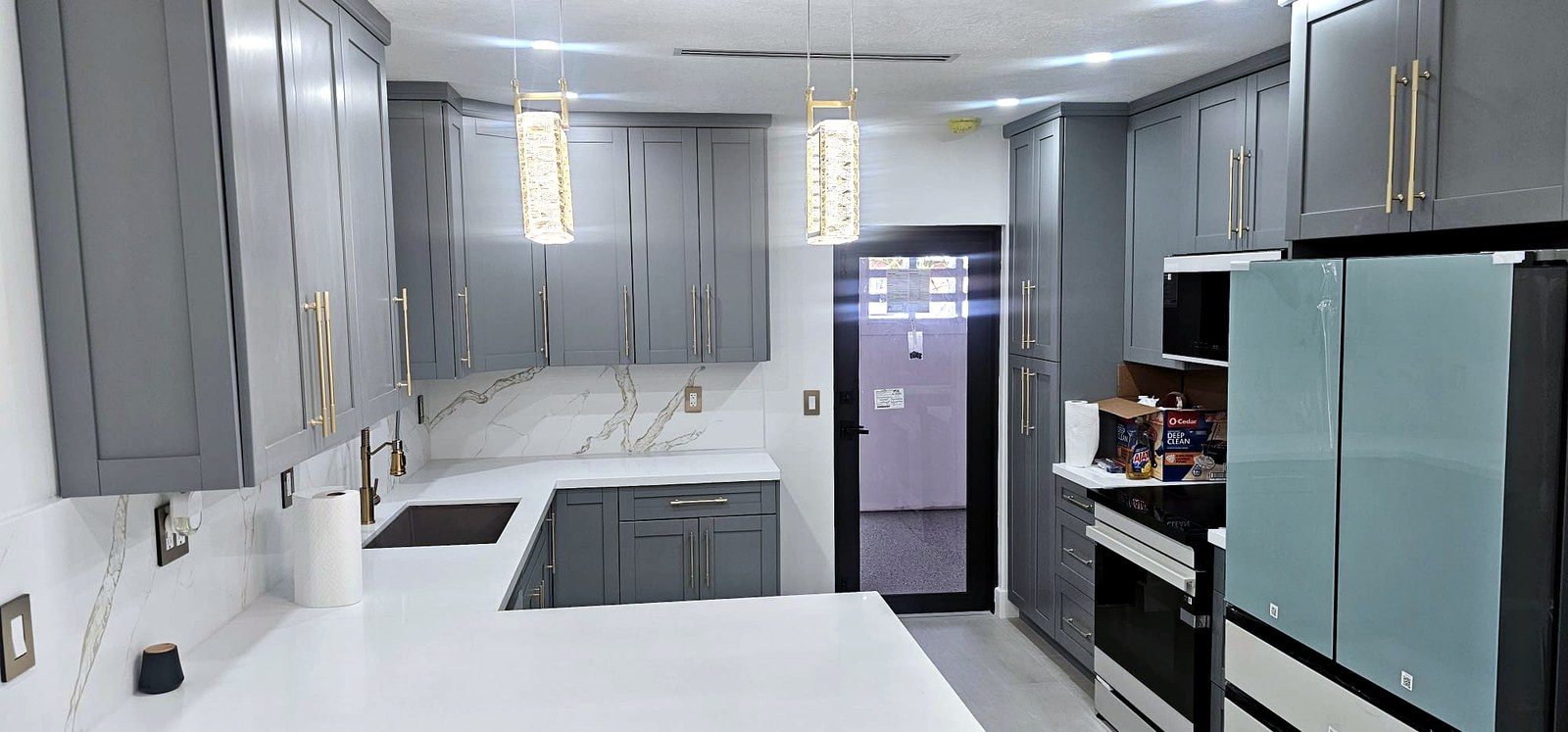 Modern gray shaker kitchen with gold hardware and crystal pendants